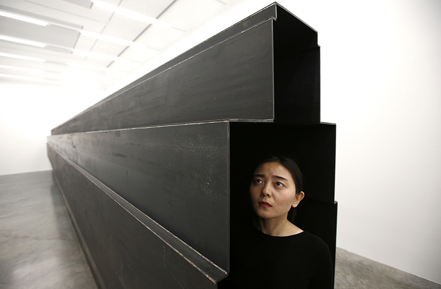 A member of the gallery poses for a photograph inside a piece called "Passage", by artist Antony Gormley, which forms part of an exhibition entitled "Fit", at the White Cube gallery in London, Britain September 29, 2016.   REUTERS/Peter Nicholls