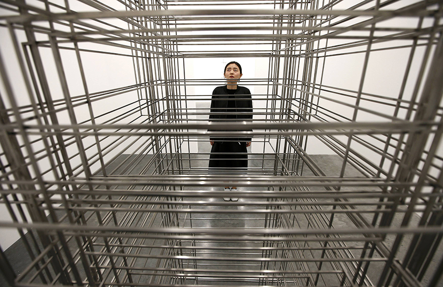 A member of the gallery poses for a photograph next to a piece called "Fit", by artist Antony Gormley, which forms part of an exhibition entitled "Fit", at the White Cube gallery in London, Britain September 29, 2016. REUTERS/Peter Nicholls